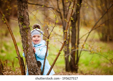 Small girl standing behind a tree