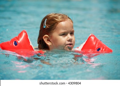 Small Girl Swimming In Pool With Water Wings