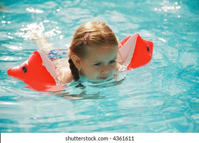 Small Girl Swimming In Pool With Water Wings