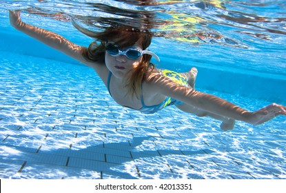 Small Girl Swimming Under Water In The Swimming Pool