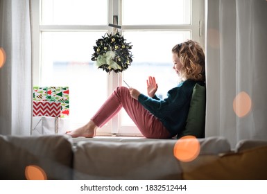 Small girl with tablet sitting indoors at home at Christmas, having video call. - Powered by Shutterstock