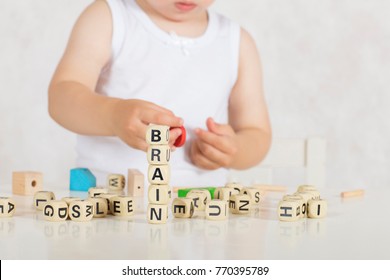 Small girl of two years composes words from letters. Closeup