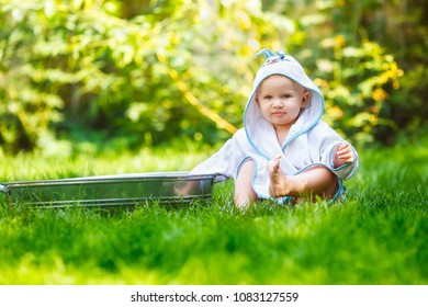 A Small Girl Wearing Bathrobe Sitting Near A Basin Bathes  On The Outside.  Copy Space