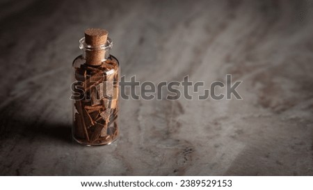 A small glass bottle filled with organic cinnamon ( Cinnamomum verum) or dalchini is placed on a marble background.