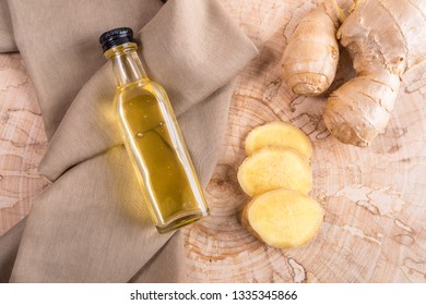 Small glass bottle of ginger oil on brown cloth and fresh ginger on wooden saw cut.  - Powered by Shutterstock