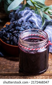 Small glass jar with homemade  haskap berry jam, on wooden background with bowl of fresh haskap (honeysuckle, honeyberry) berries, copy space - Shutterstock ID 2172468347