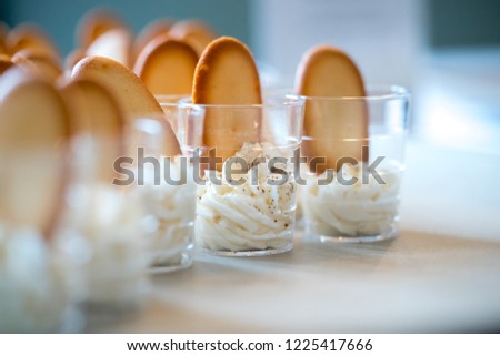 Small glasses with sample of cheesecake mousee and italian biscuits  at a tasting.