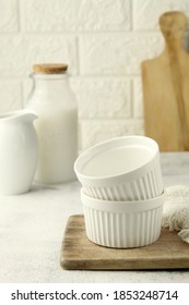 Small Glazed Ceramic Ramekin On Wooden Tray. Empty Ramekins With A Bottle Of Milk Behind. Selective Focus.