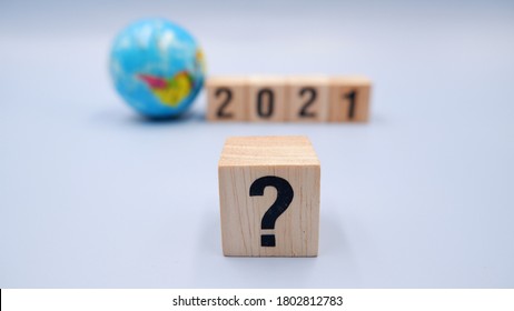 Small globe with 2021 wooden blocks and question mark symbol. Concept of world business trends, what happens with global situation during the financial crisis due to coronavirus impact.