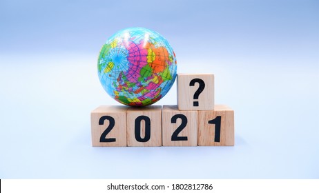 Small globe with 2021 wooden blocks and question mark symbol. Concept of world business trends, what happens with global situation during the financial crisis due to coronavirus impact.
