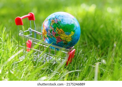 Small Globe In Supermarket Shopping Cart Depicting Russia, Belarus, Kazakhstan, China, India, Europe On Green Grass In Summer. World Sale And Internet Sales Concept. World Hunger And Crisis Concept