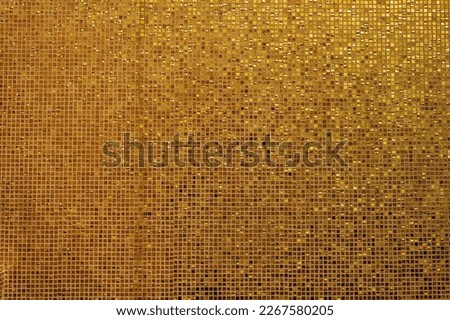Small gold tile texture. Small golden tiles arranged to fit it into background. Shiny golden mosaic background with small square, glazed tiles in rows