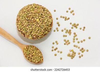 Small grains of natural green lentils in a decorative plate and in a wooden spoon