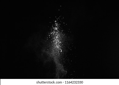Small granite rock stone fly isolated on black background. Stone with white powder splash on dark background.