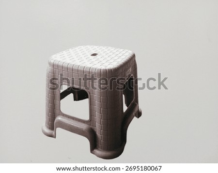 A small gray plastic stool with a checkered woven pattern.