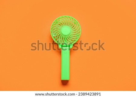 Small green electric fan on orange background