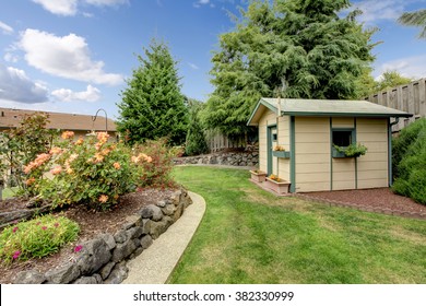 Small green fenced back yard with garden and shed.