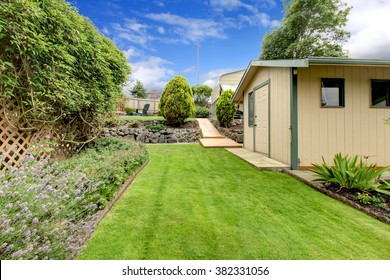 Small Green Fenced Back Yard With Garden And Shed.