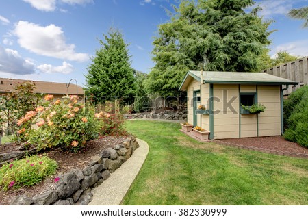 Small green fenced back yard with garden and shed.