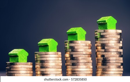 Small green houses standing on stacks of coins. - Shutterstock ID 572835850