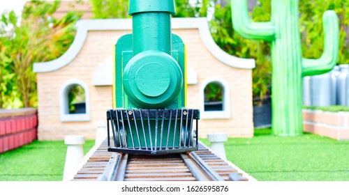 A Small Green Model Train Running On A Rail