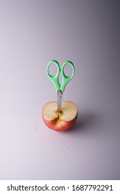 The Small Green Scissors Stab In The Half Of Red Fresh Apple.It Is A Super Cool Wallpaper.