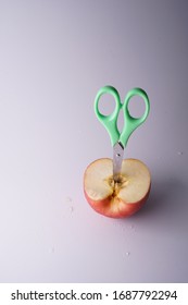 The Small Green Scissors Stab In The Half Of Red Fresh Apple.It Is A Super Cool Wallpaper.