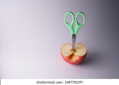 The Small Green Scissors Stab In The Half Of Red Fresh Apple.It Is A Super Cool Wallpaper.