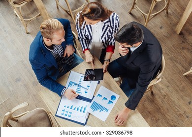 Small Group Of Business People At A Meeting In A Cafe. Selective Focus On Papers And Table.