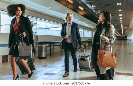 Small Group Of Business People Walking Together In Airport Terminal. Business Travelers With Luggage Going To Board Their Flight.