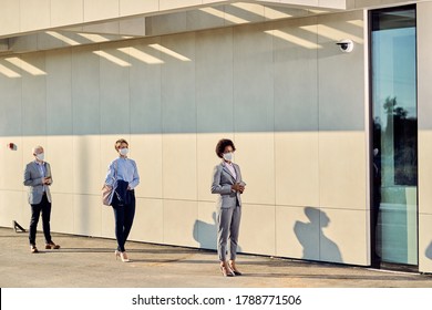 Small Group Of Business People Wearing Protective Face Masks While Waiting In Line On A Safe Distance During Coronavirus Epidemic. 