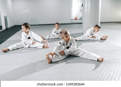 Small group of Caucasian sporty children stretching and warming up before their taekwondo training.