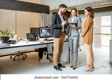 Small Group Of Creative Office Employees Working With Digital Tablet, During A Meeting In The Modern Office Of Architectural Firm