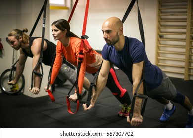 Small Group Doing Exercises In A Gym With Straps.