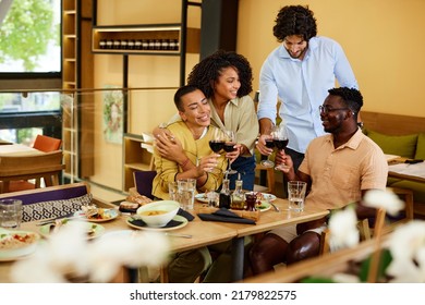 A Small Group Of Friends In A Restaurant Is Toasting With Red Wine And Having Fun.