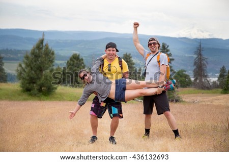 Small group of hikers, fooling around, two men holding woman up, laughing, celebrating