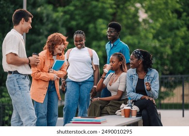 Small group of multicultural students sitting and standing at university campus and taking a coffee break between lectures. Smiling college students drinking coffee and having break at campus. - Powered by Shutterstock