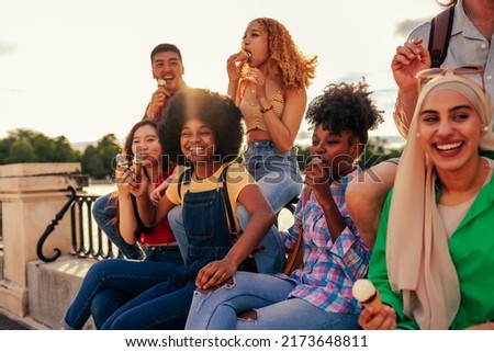 A small group of multiethnic friends are hanging out in the city and eating ice cream