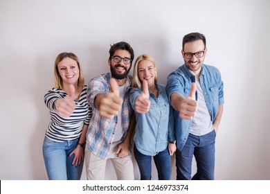 Small Group Of People Giving Thumbs Up While Standing Against The White Wall. Start Up Business Concept.