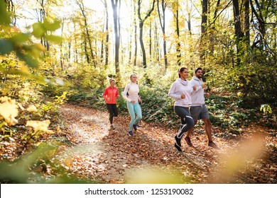 Small group of people running in woods in the autumn.