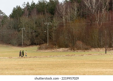 Small Group Of People Walking Across A Field.