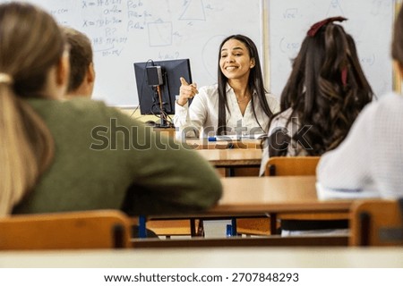 A small group of students is in their elementary classroom while a teacher guides them through a math and geometry lesson. She is asking questions and helping them stay focused as they work