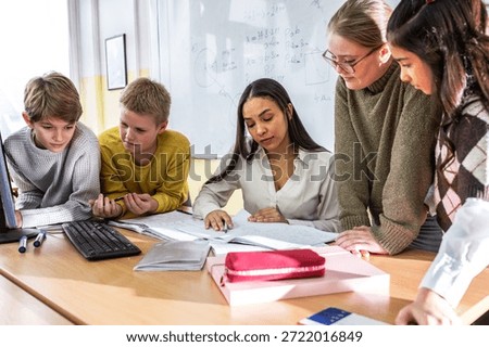 	
A small group of students is in their elementary classroom while a mixed-race teacher guides them through a math and geometry lesson. She is asking questions and helping them stay focused as they work	
