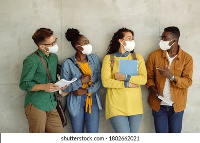 Small Group Of University Students Wearing Protective Face Masks While Talking By The Wall In A Hallway. 