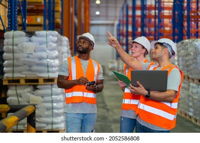 A Small Group Of Warehouse Workers Have A Briefing In A Large Distribution Center. Concept Of Teamwork And Occupation.