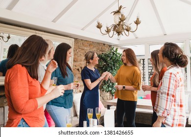 Small Group Of Women With A Mixed Age Range At A Beauty Product Party. The Beauty Product Sales Representative Is Standing Talking About The Products.