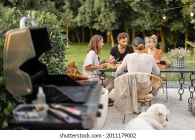 Small group of a young friends have a lunch outdoors, eating grilled vegetables and fish and having fun at backyard with grill - Powered by Shutterstock