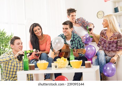 A Small Group Of Young People At The Home Party, Enjoy The Sounds Of The Acoustic Guitar, Drinking Wine And Beer.