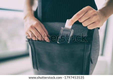 Small hand sanitizer bottle to go in woman's purse. Girl using portable sanitizer in bag, when going on commute, for disinfecting hands as Covid 19 prevention.