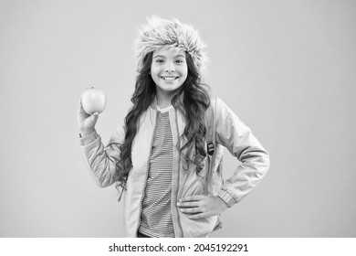 Small Happy Girl Earflap Hat Eat Apple. End Of Winter Semester. Holiday And Vacation. Kid Pink Backdrop. Teen Daily Life. Education And Happy People Schoolgirl With Books After Lesson. School Break